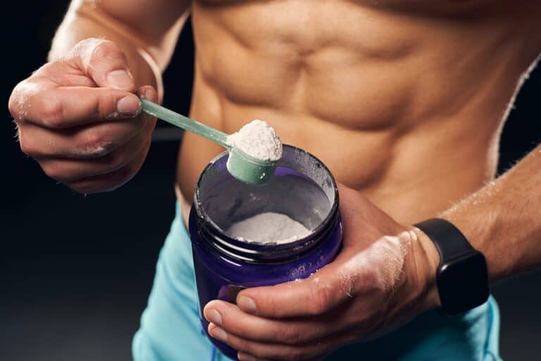 fit man with creatine powder scoop